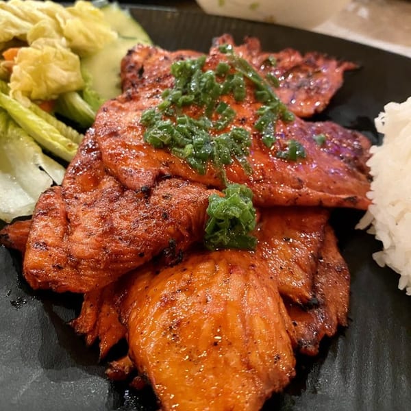 Grilled chicken topped with green onions, served with white rice and a side salad.