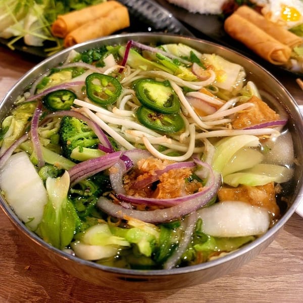 A bowl of Pho Saigon 8's Vietnamese pho with noodles, vegetables, and sliced jalapeños.